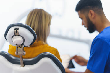 Rear view of multiracial dentist and patient sitting in dentists chair. - HPIF10581