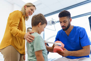 Junger Zahnarzt zeigt kleinen Jungen, wie man die Zähne reinigt, Konzept der Mundhygiene für Kinder, Prävention und Zahngesundheit. - HPIF10590