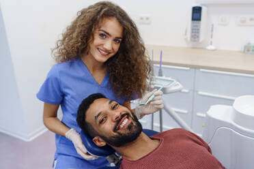 Young woman dentist doing doing preventive examination to the multiracial man. - HPIF10606