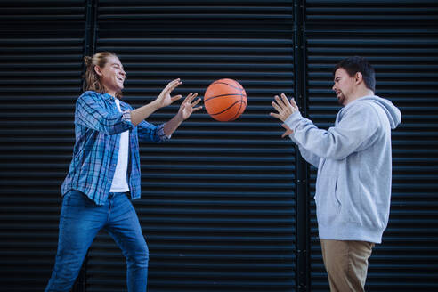 Ein Mann mit Down-Syndrom spielt mit seinem Freund Basketball im Freien. Konzept der Freundschaft und Integration von Menschen mit Behinderung in die Gesellschaft. - HPIF10615