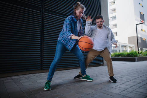 Ein Mann mit Down-Syndrom spielt mit seinem Freund Basketball im Freien. Konzept der Freundschaft und Integration von Menschen mit Behinderung in die Gesellschaft. - HPIF10618