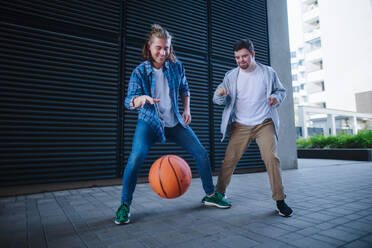 Ein Mann mit Down-Syndrom spielt mit seinem Freund Basketball im Freien. Konzept der Freundschaft und Integration von Menschen mit Behinderung in die Gesellschaft. - HPIF10619