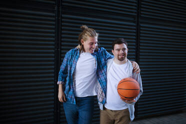 Ein Mann mit Down-Syndrom spielt mit seinem Freund Basketball im Freien. Konzept der Freundschaft und Integration von Menschen mit Behinderung in die Gesellschaft. - HPIF10621