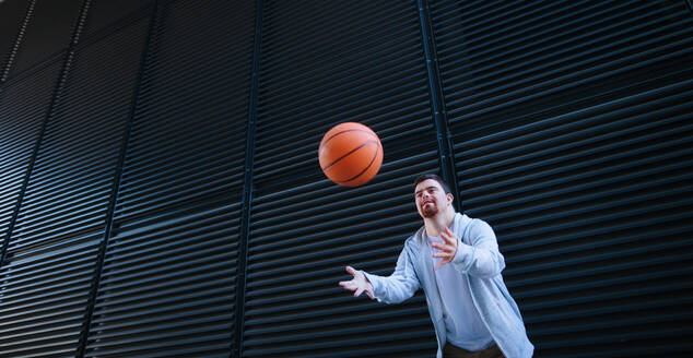 Junger Mann mit Down-Syndrom wirft einen Basketball weg. - HPIF10624