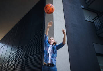 Young man throwing away a basketball ball,outdoor in city. Youth culture. - HPIF10626