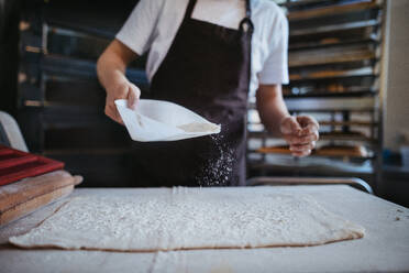 Nahaufnahme eines jungen Bäckers bei der Zubereitung von Gebäck in einer Bäckerei. - HPIF10641