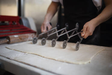 Nahaufnahme eines Bäckers bei der Zubereitung von Gebäck in einer Bäckerei. - HPIF10645