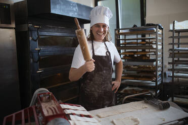 Junger Bäcker mit Kochmütze bei der Zubereitung von Gebäck in einer Bäckerei. - HPIF10653