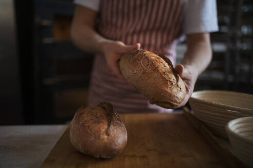 Nahaufnahme eines Bäckers mit frischem, gerade gebackenem Brot. - HPIF10659