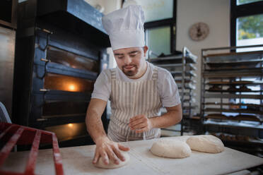 Junge Bäckerin mit Down-Syndrom bei der Zubereitung von Gebäck in einer Bäckerei. Konzept der Integration von Menschen mit Behinderungen in die Gesellschaft. - HPIF10677