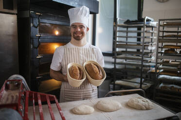 Junge Bäckerin mit Down-Syndrom bei der Zubereitung von Gebäck in einer Bäckerei. Konzept der Integration von Menschen mit Behinderungen in die Gesellschaft. - HPIF10679