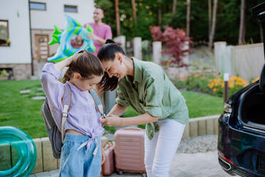 Young family preparing for summer holiday, putting suitcases in a car trunk. - HPIF10712