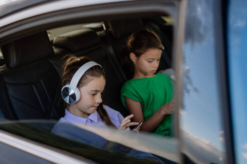 Kleine Schwestern, die in einem Auto sitzen, Musik hören und auf eine Autofahrt warten. - HPIF10720