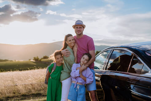Glückliche Familie auf einer Autoreise mit Pause in der Natur, neben ihrem Elektroauto. - HPIF10732
