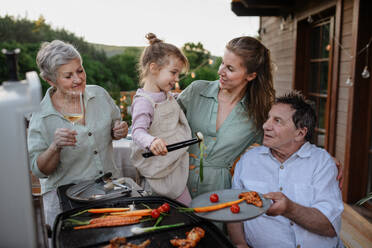 Eine Mehrgenerationenfamilie beim Grillen auf der Terrasse im Sommer während einer Gartenparty - HPIF10746