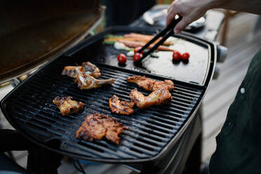 An unrecognizable man grilling meat and vegetable on grill during family summer garden party, close-up - HPIF10747