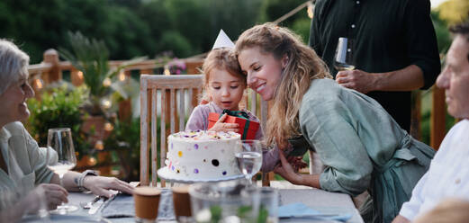 Eine Mehrgenerationenfamilie feiert den Geburtstag eines kleinen Mädchens und feiert eine Gartenparty auf der Terrasse. - HPIF10748