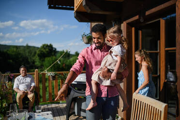 Eine Mehrgenerationen-Familie feiert draußen im Hinterhof auf einer Terrasse. - HPIF10750