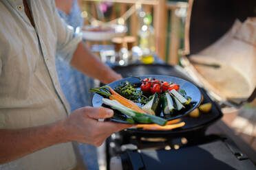 Ein nicht erkennbarer Mann grillt Gemüse auf einem Grill während einer Familien-Sommergartenparty. - HPIF10754