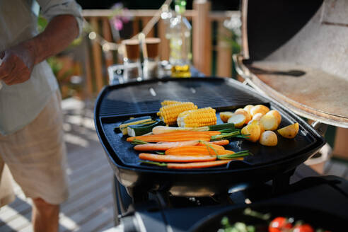 Ein nicht erkennbarer Mann grillt Gemüse auf einem Grill während einer Familien-Sommergartenparty. - HPIF10755