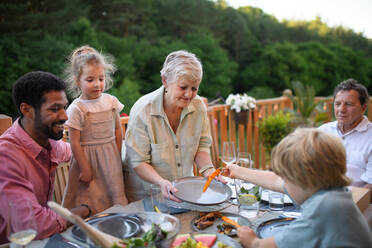 Mehrgenerationen-Familie beim Abendessen auf einer Grillparty im Freien. - HPIF10765