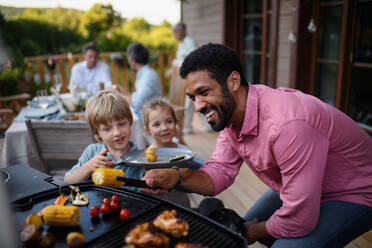 Eine Mehrgenerationen-Familie feiert draußen im Hinterhof auf einer Terrasse. - HPIF10769