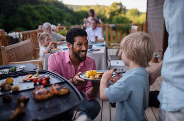 Ein Vater, der Fleisch und Gemüse auf dem Grill grillt, während einer Familien-Sommergartenparty. - HPIF10771