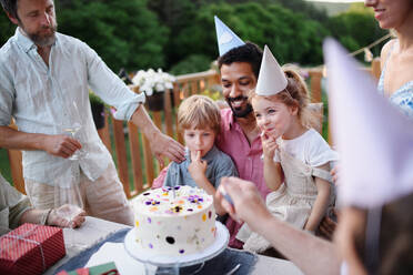 A multi generation family celebratiing birthday and have garden party outside in the backyard on patio. - HPIF10778