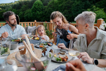 Mehrgenerationen-Familie beim Abendessen auf einer Grillparty im Freien. - HPIF10780