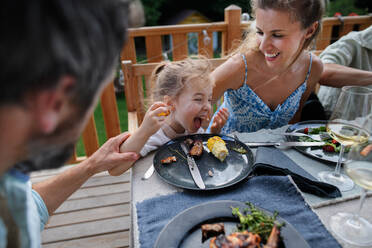 Eine Familie, die auf einer Terrasse bei einer Grillparty zu Abend isst, Spaß hat und es genießt. - HPIF10781