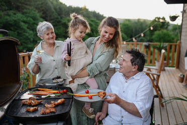 Eine Mehrgenerationenfamilie beim Grillen auf der Terrasse im Sommer während einer Gartenparty - HPIF10788