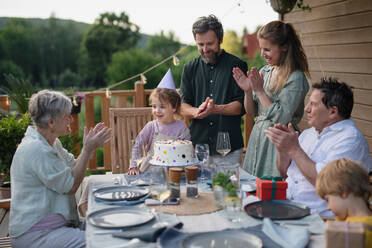 A multi generation family celebratiing birthday and have garden party outside in the backyard on patio. - HPIF10790