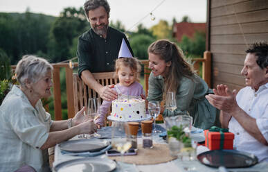 A multi generation family celebratiing birthday and have garden party outside in the backyard on patio. - HPIF10791