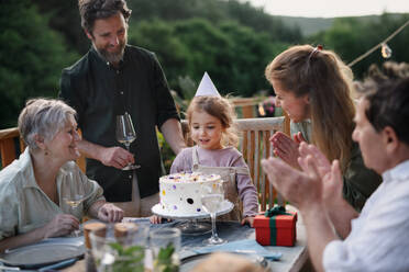 Eine Mehrgenerationenfamilie feiert den Geburtstag eines kleinen Mädchens und feiert eine Gartenparty auf der Terrasse. - HPIF10792
