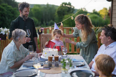 A multi generation family celebratiing birthday and have garden party outside in the backyard on patio. - HPIF10793