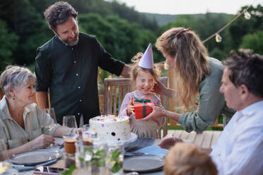 Eine Mehrgenerationenfamilie feiert den Geburtstag eines kleinen Mädchens und feiert eine Gartenparty auf der Terrasse. - HPIF10795