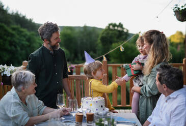 A multi generation family celebratiing birthday and have garden party outside in the backyard on patio. - HPIF10797