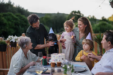 Eine Mehrgenerationenfamilie feiert den Geburtstag ihres Hundes und feiert eine Gartenparty auf der Terrasse. - HPIF10799