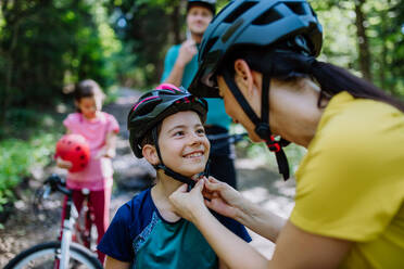 A young family with little children preapring for bike ride, standing with bicycles in nature. - HPIF10806