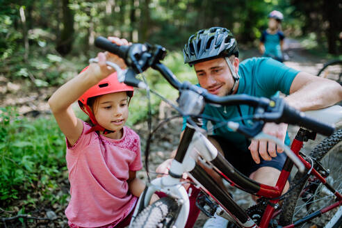 Vater, der seiner Tochter während eines Familienausflugs in der Natur ein Fahrrad schenkt. - HPIF10809