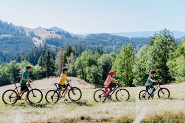 A young family with little child pushing bicycles on trail in nature in summer. - HPIF10816