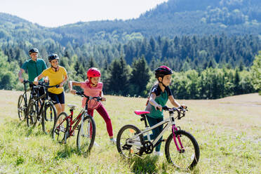 Young family with little children at a bike trip together in nature. - HPIF10817