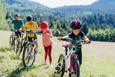 Junge Familie mit kleinen Kindern bei einem gemeinsamen Fahrradausflug in der Natur. - HPIF10818