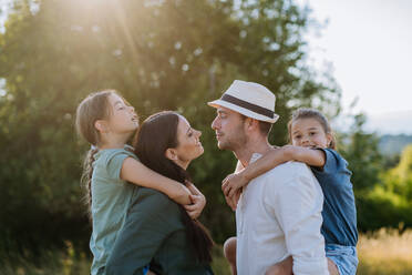 Portrait of young couple with their daughters in nature, kissing. Side view. - HPIF10829