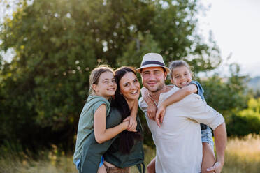 A happy family with two small daughters standing outdoors in summer nature. - HPIF10832