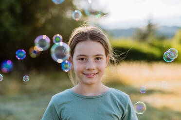 Portrait of a beautiful little girl smiling in nature, with the bubbles in the background. - HPIF10839