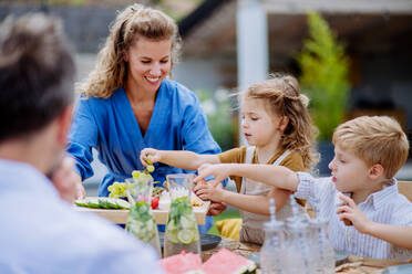 Eine Familie feiert eine Gartenparty, die Kinder essen Snacks, lachen und haben Spaß. - HPIF10890