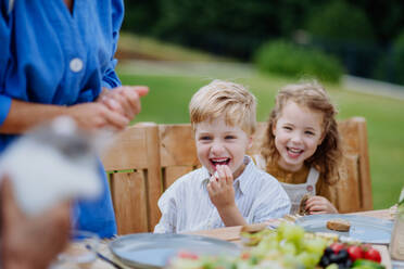 Glückliche Kinder, die das Gartenfest mit ihrer Familie genießen, Spaß haben und gemeinsam essen. - HPIF10892