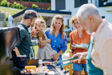 Eine Mehrgenerationenfamilie, die im Sommer während einer Gartenparty im Hinterhof grillt - HPIF10901