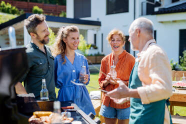 Eine Mehrgenerationenfamilie, die im Sommer während einer Gartenparty im Hinterhof grillt - HPIF10902